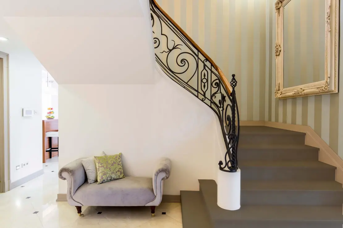 Mikrocementové schodiště v domě v klasickém stylu a s tapetami na stěnách