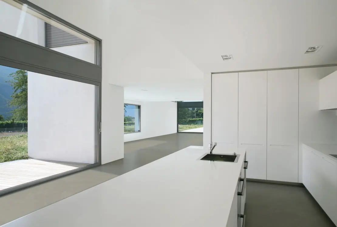 Microcement on the floor of a spacious kitchen, with an independent island and views of the garden