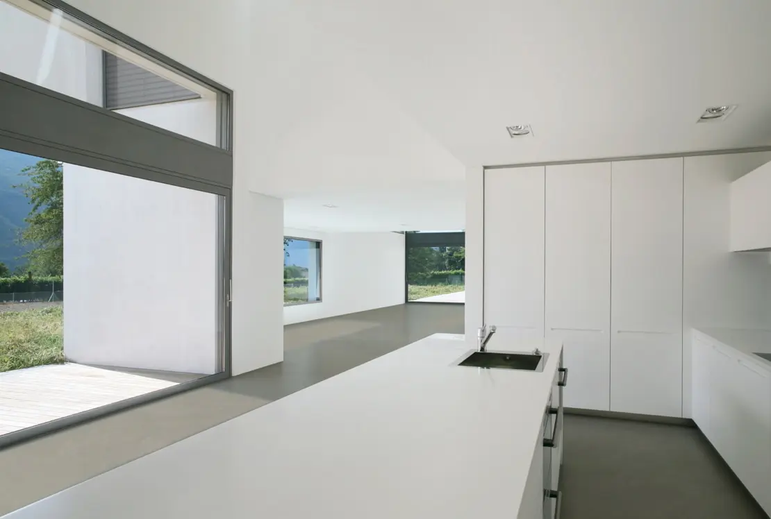 Microcement on the floor of a spacious kitchen, with a separate island and views of the garden