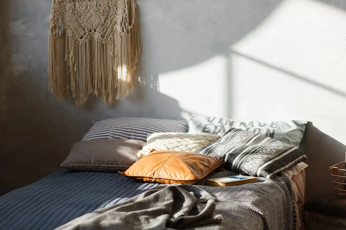 Estilo boho chic como decoración de un dormitorio con pared de microcemento