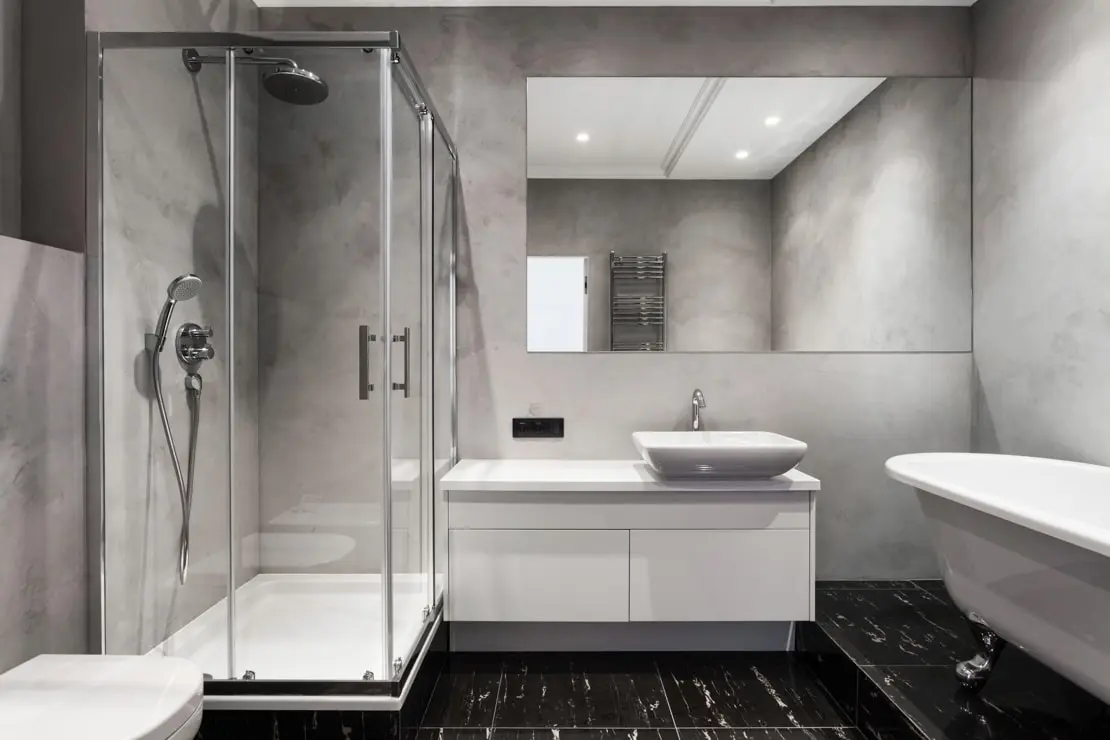 Microcemento en las paredes de un baño con doble altura y una bañera flotante