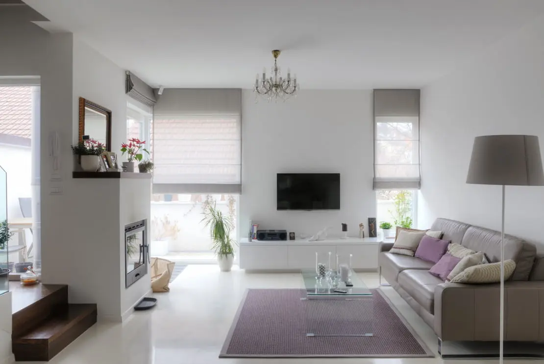 Salón decorado con una escalera de madera, sofa marrón, mesa de vidrio y chimenea