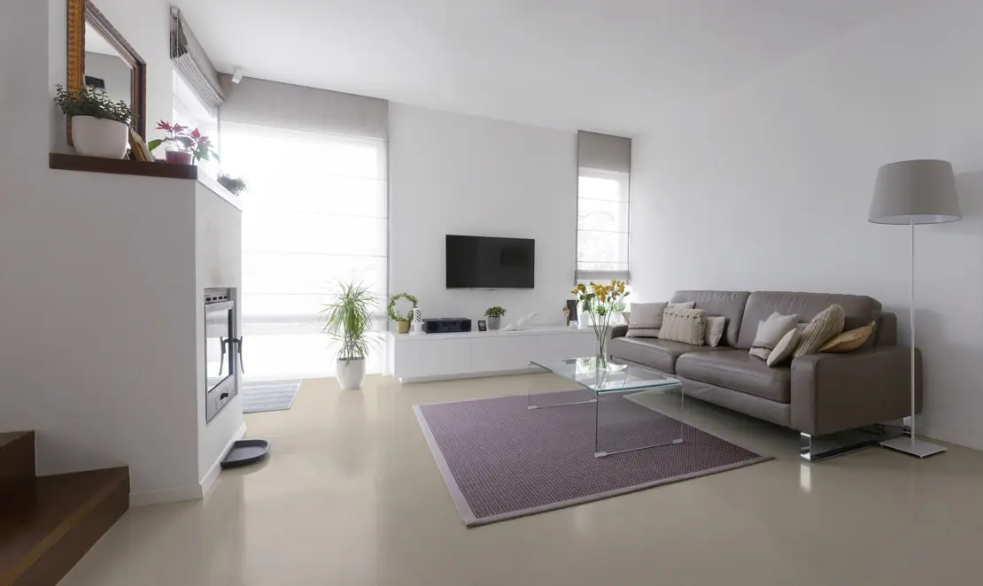 Mikrocement padló egy dupla magasságú nappaliban kandallóval, fehér falakkal és fehér árnyalatokkal a falakon