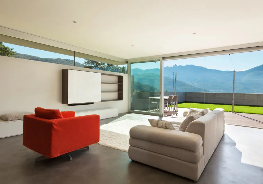 Lyxigt vardagsrum med microcement på golvet och utsikt över en terrass med trädgård